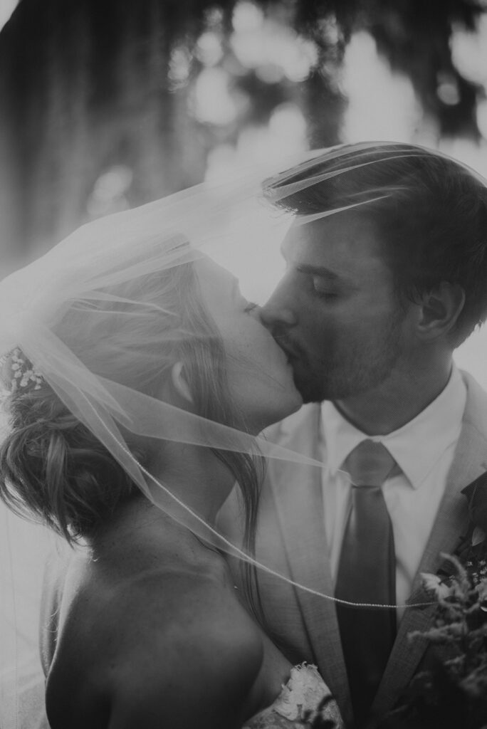 bride and groom kissing under veil