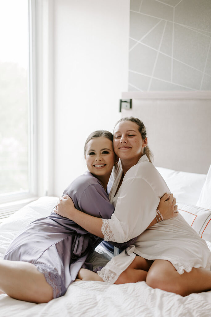 bridal party getting ready on bed in white and purple robes