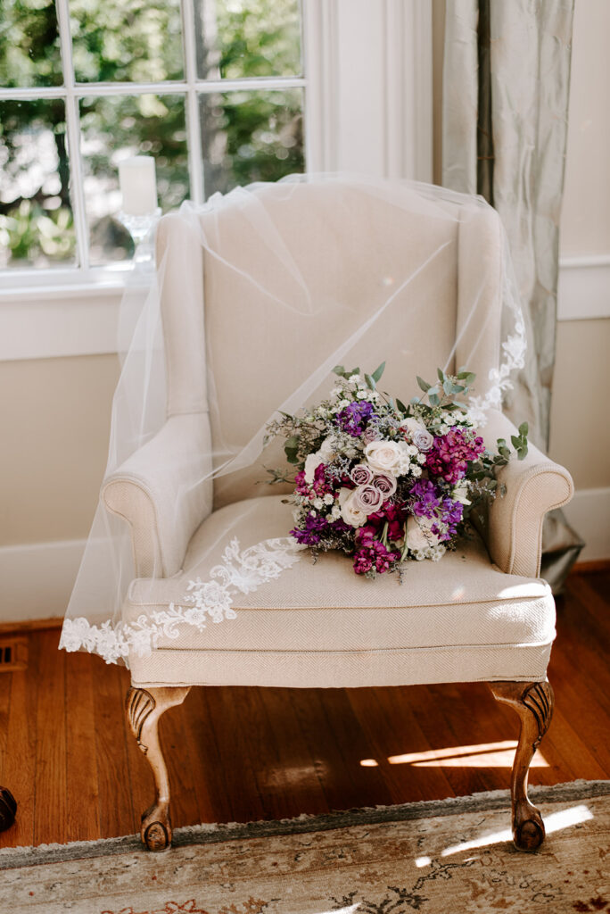 bridal veil with purple bouquet on a chair