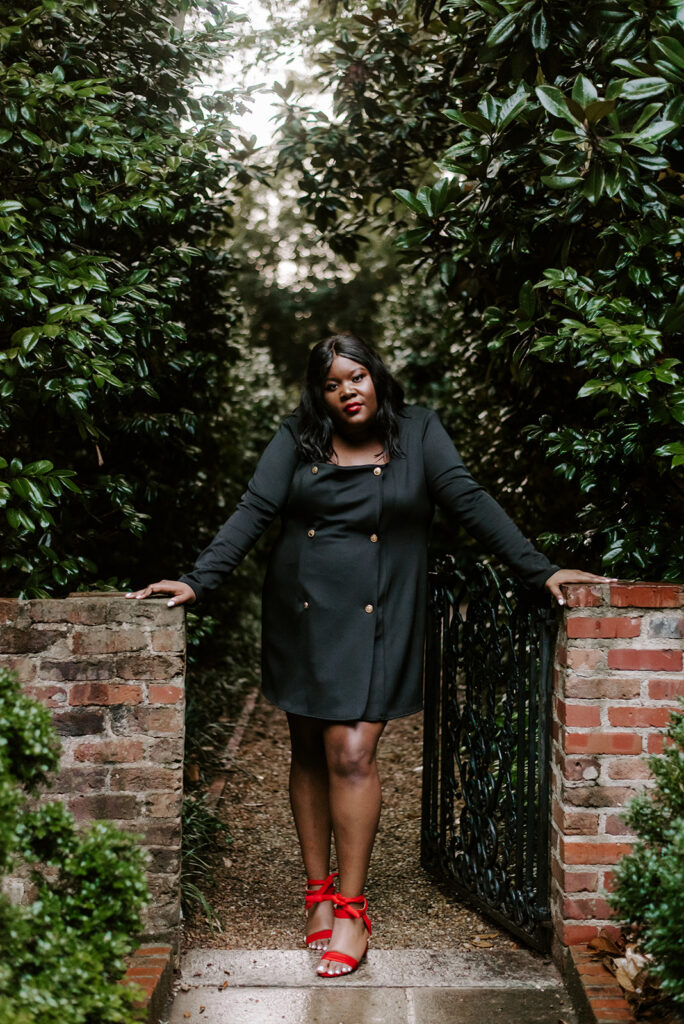 graduate posing by a gate at founder's garden