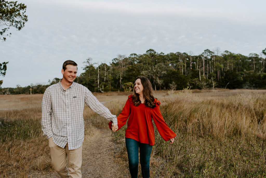 couple walking and laughing together at skidaway island for their engagement session