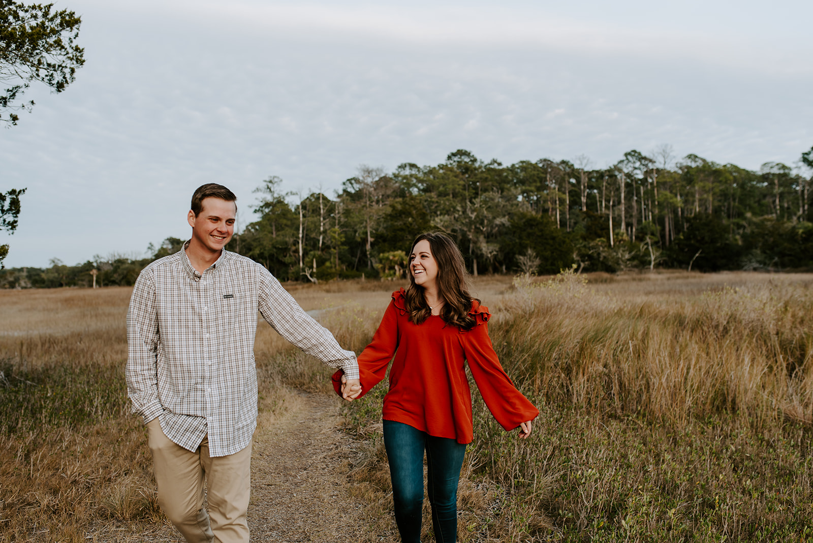 couple walking and laughing together at skidaway island for their engagement session