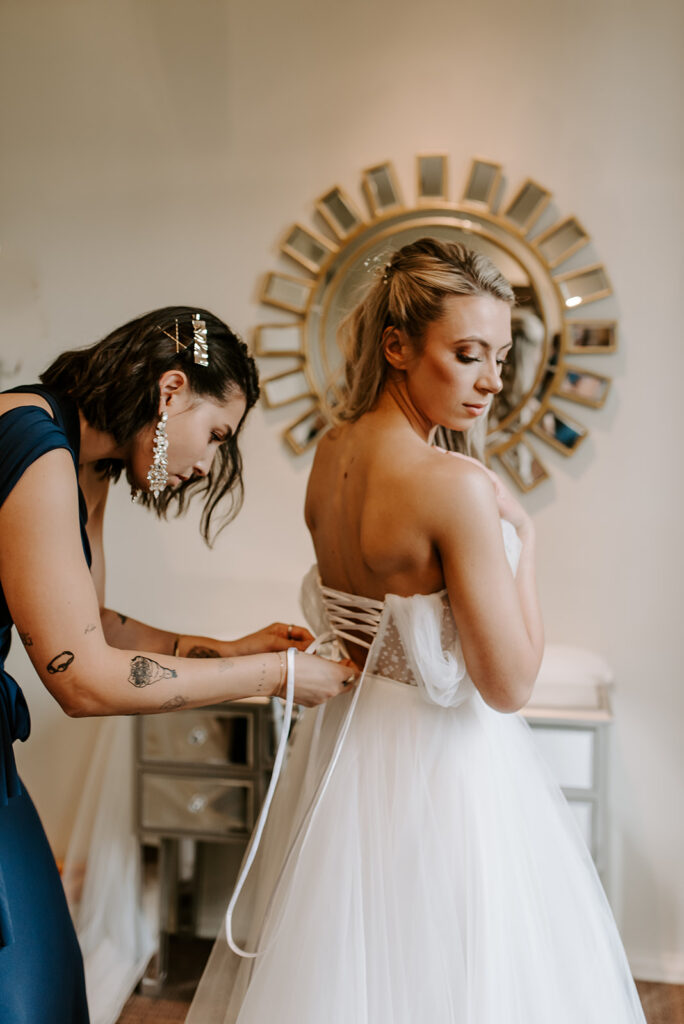 bridesmaid buttoning up the bride's wedding dress at summerour studio