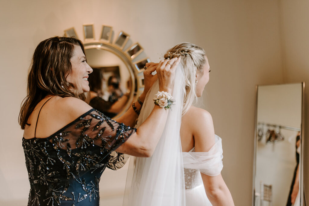 mom wearing a navy blue formal gown putting on bride's veil