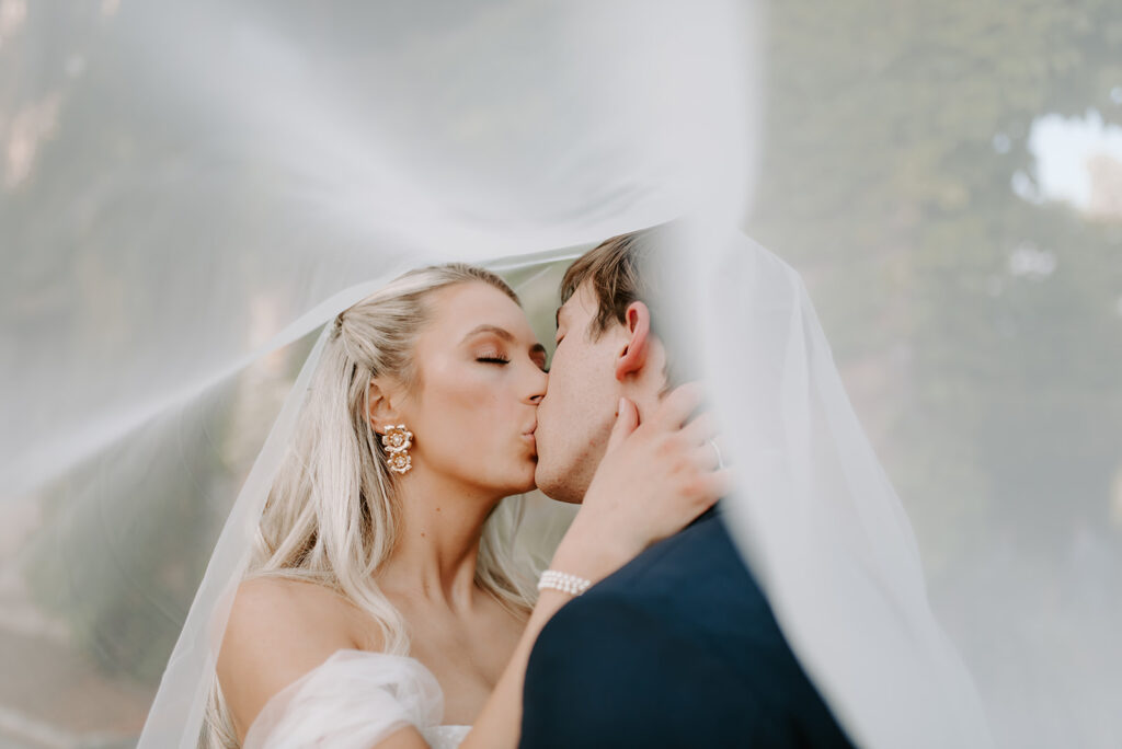 bride and groom kissing under their veil at summerour studio