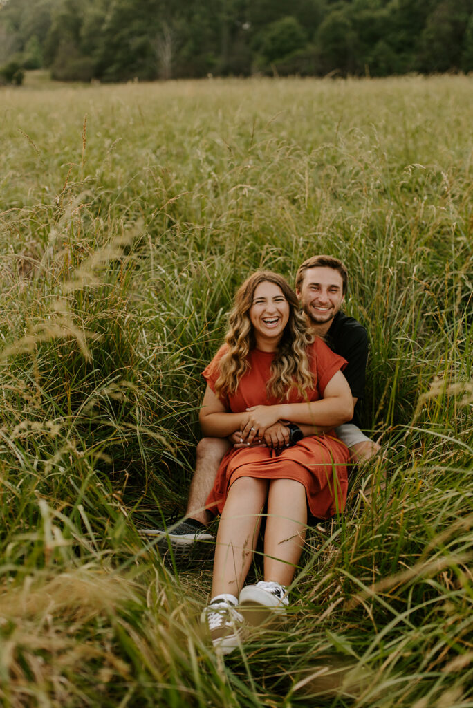 engaged couple laughing in the grass at vaughter's farm