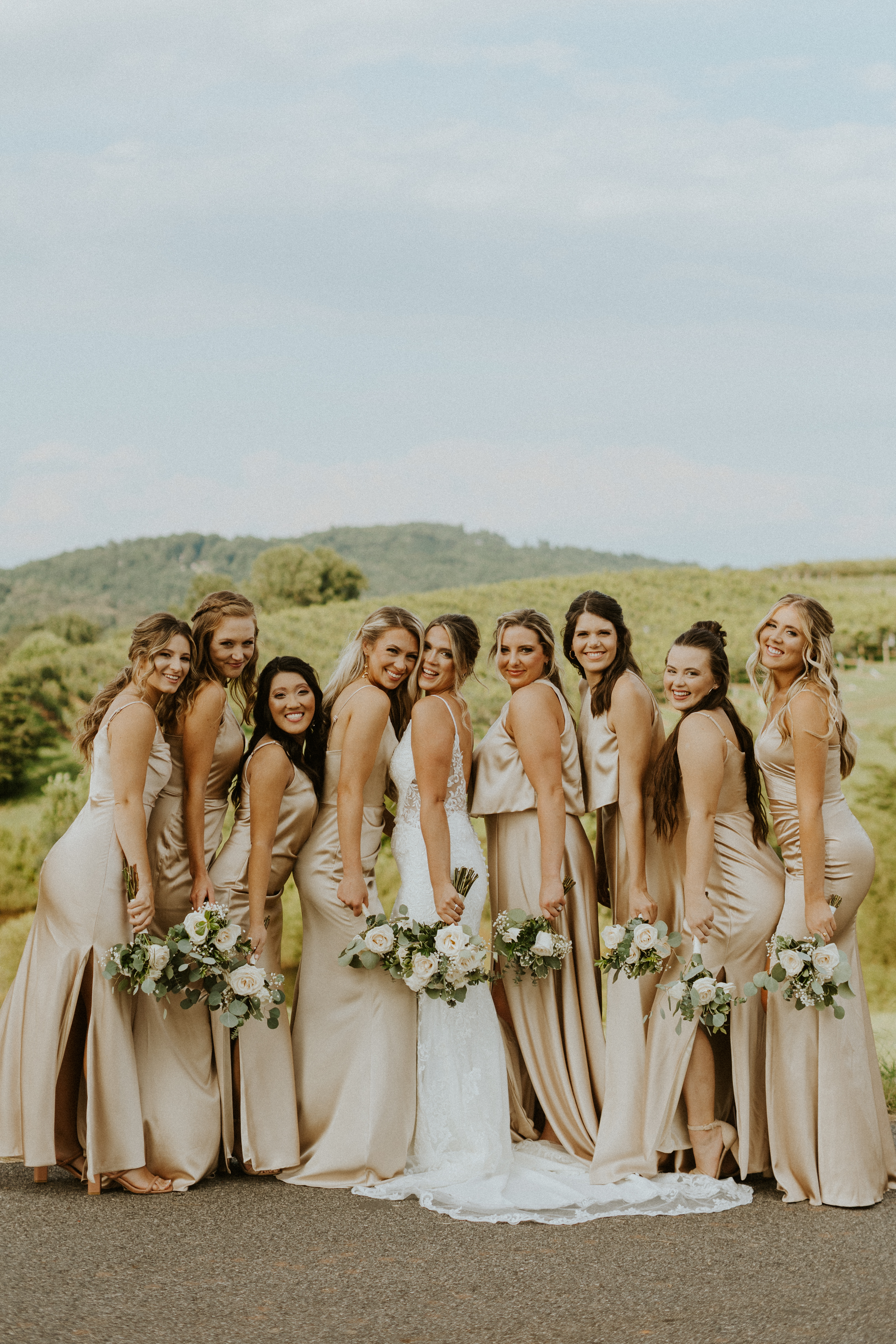bridesmaids in champagne sating dresses with white and green floral bouquets