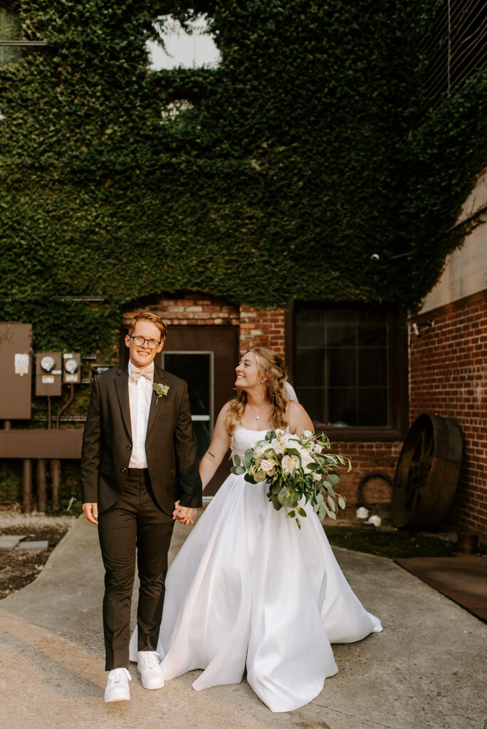 bride and groom walking hand in hand at factory at walton mill in monroe georgia