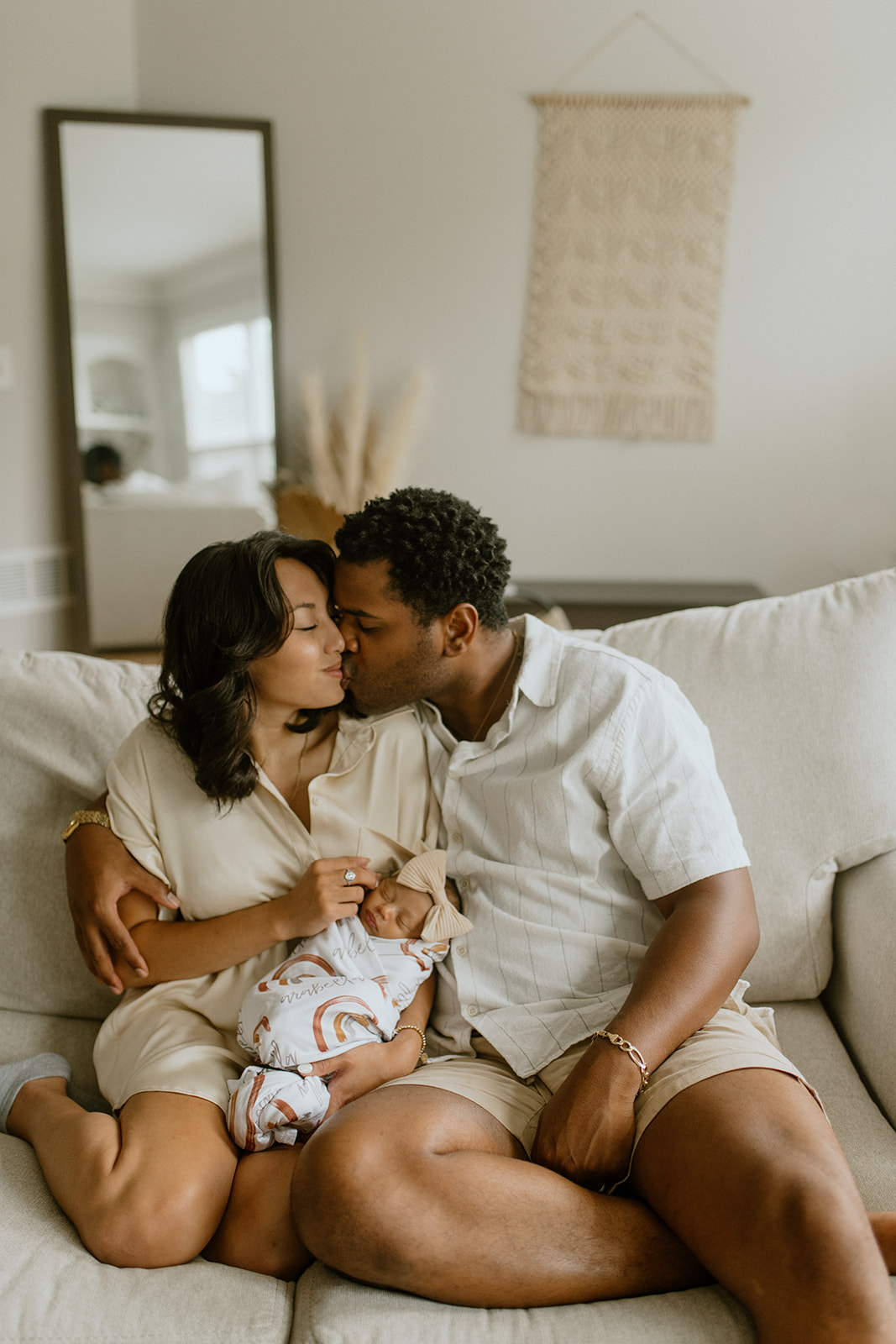 husband and wife kissing while holding baby