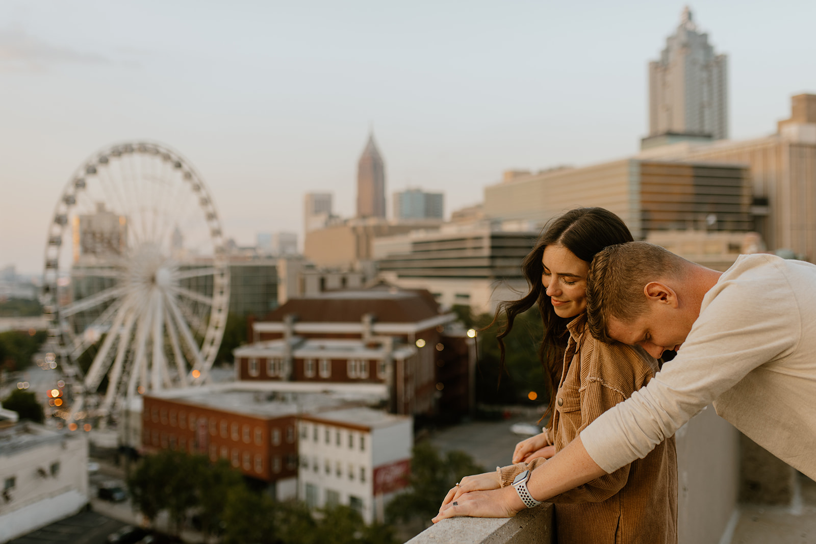couple snuggling on atlanta rooftop with skyview ferris wheel in the background
